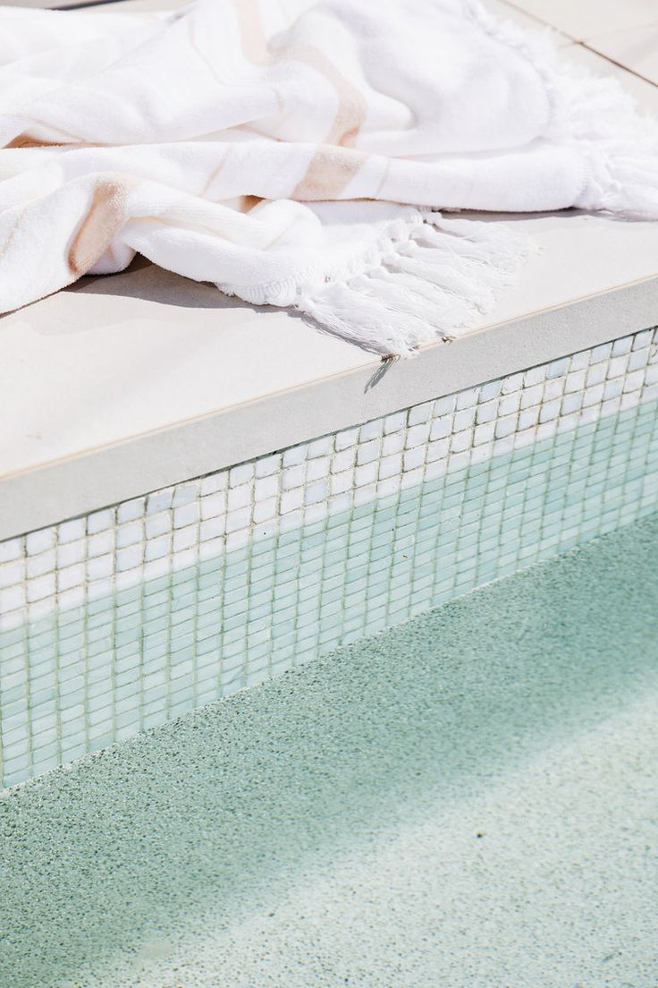 a towel sitting on top of a swimming pool next to a white tiled wall and floor