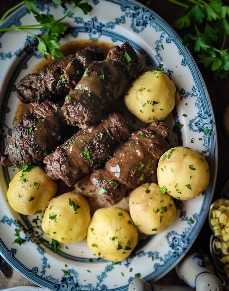 a blue and white plate topped with meat and potatoes