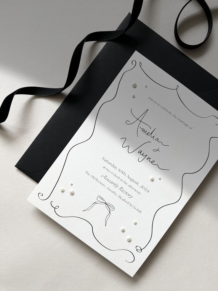 a black and white wedding card with a ribbon