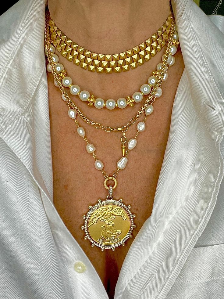 This feminine but wildly striking coin pendant is our newest edition to our popular coin collection. Large Brushed gold Winged Victoria Coin set in a crystal and pearl bezel with white freshwater pearl 14k gold chain. Measures 21” long and we added some chain you can adjust the length to wear shorter, lobster clasp closure. Coin is a reproduction, measures 50mm total, and is brass with gold plate. All materials are free from cadmium, lead, and nickel. Three Piece Set includes Winged Victoria nec Inexpensive Jewelry, Looks Street Style, Gold Necklace Women, Gold Necklace Designs, Coin Jewelry, Custom Jewelry Design, Stunning Jewellery, Coin Necklace, Coin Pendant