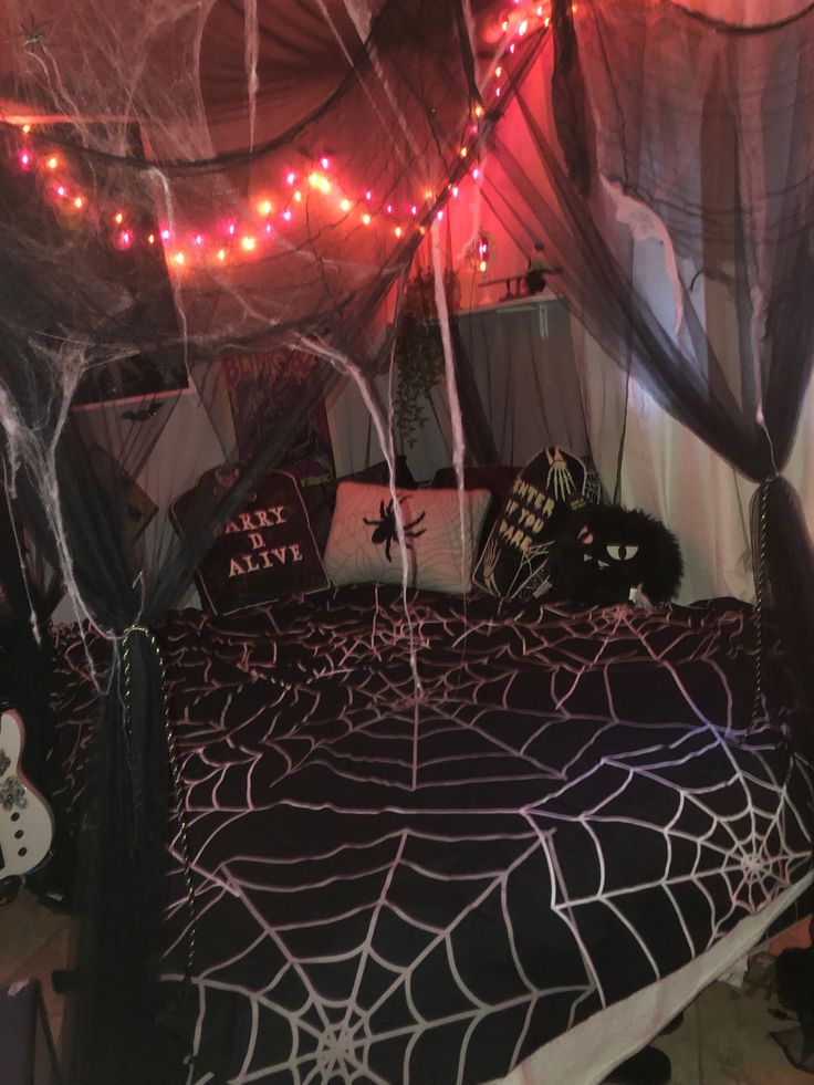 a bed covered in spider webs and halloween lights