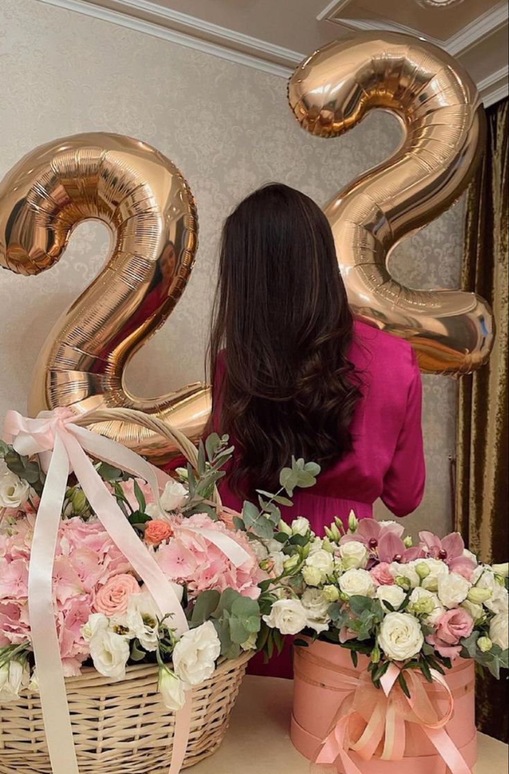 a woman sitting in front of a basket with flowers and balloons that say twenty two