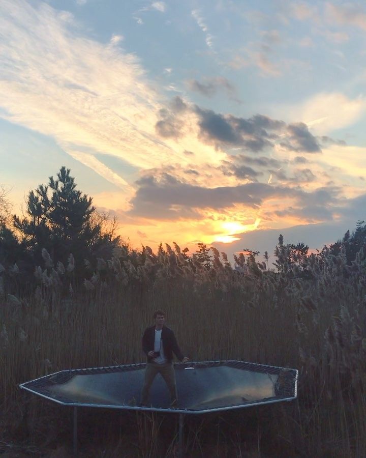 a man sitting on top of a surfboard in the middle of a grass field