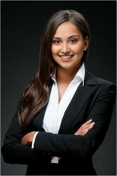 a woman with her arms crossed posing for a photo in front of a black background