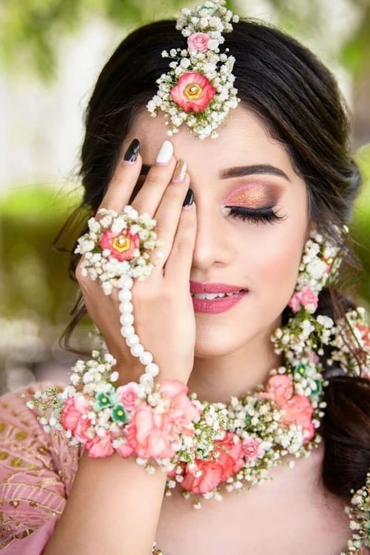 a woman with flowers in her hair and pearls around her neck, holding her hands to her face