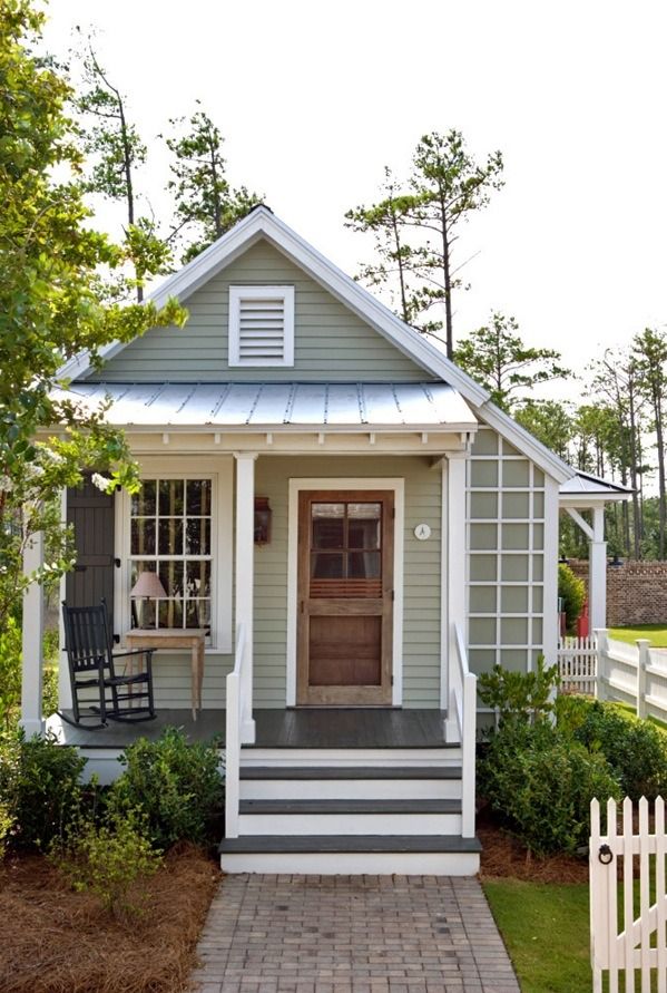 a small gray house with white trim and steps leading up to the front door is shown