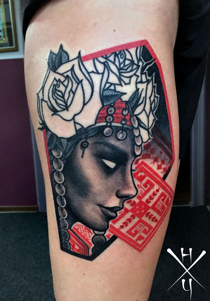 a woman's leg with a tattoo on it and flowers in her hair is shown