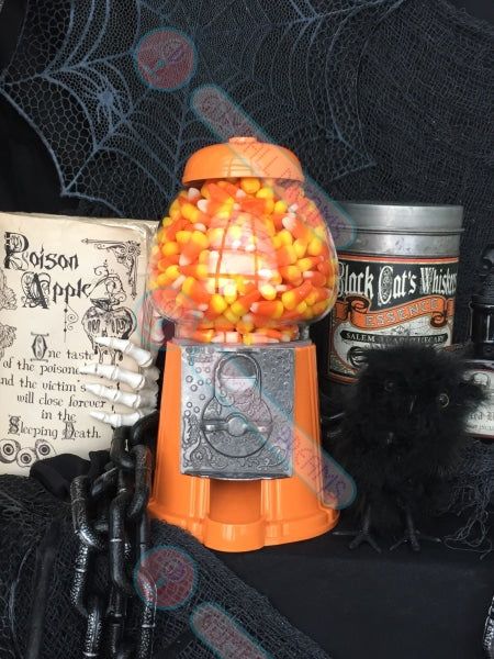 an orange candy dispenser sitting on top of a table next to halloween decorations