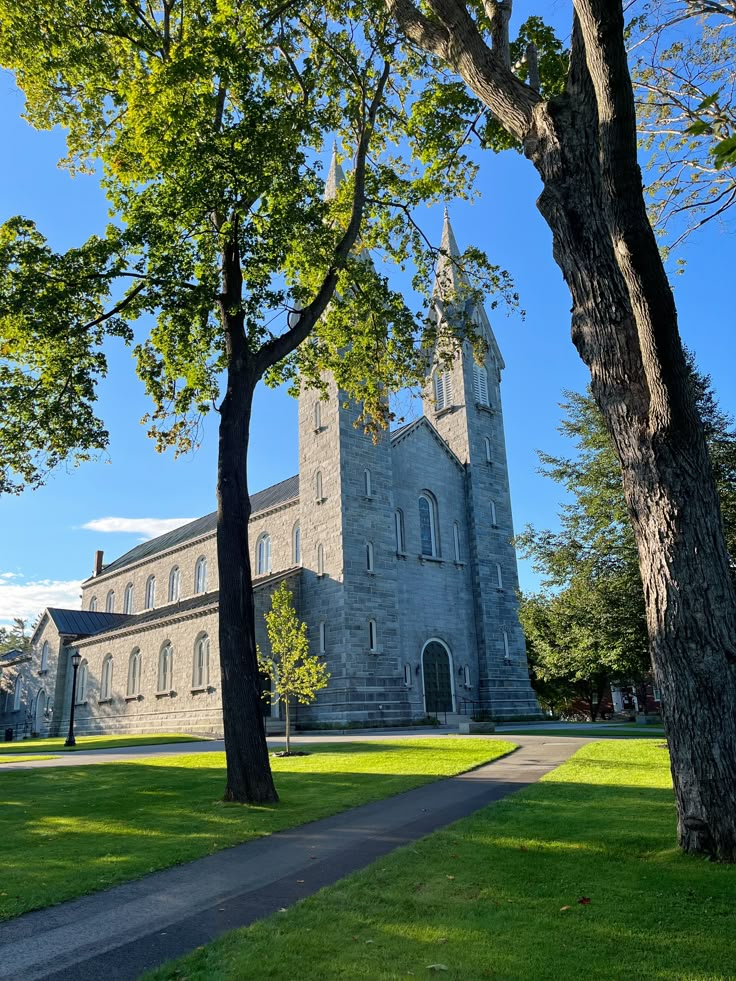 an old church with trees in the foreground and a path leading up to it