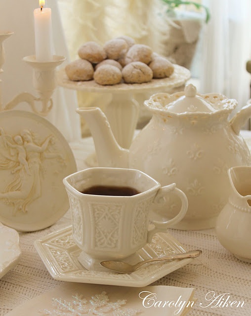 a table topped with white dishes and cups filled with coffee next to cookies on top of each other