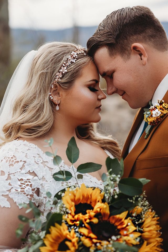 a bride and groom standing next to each other with sunflowers in their hair