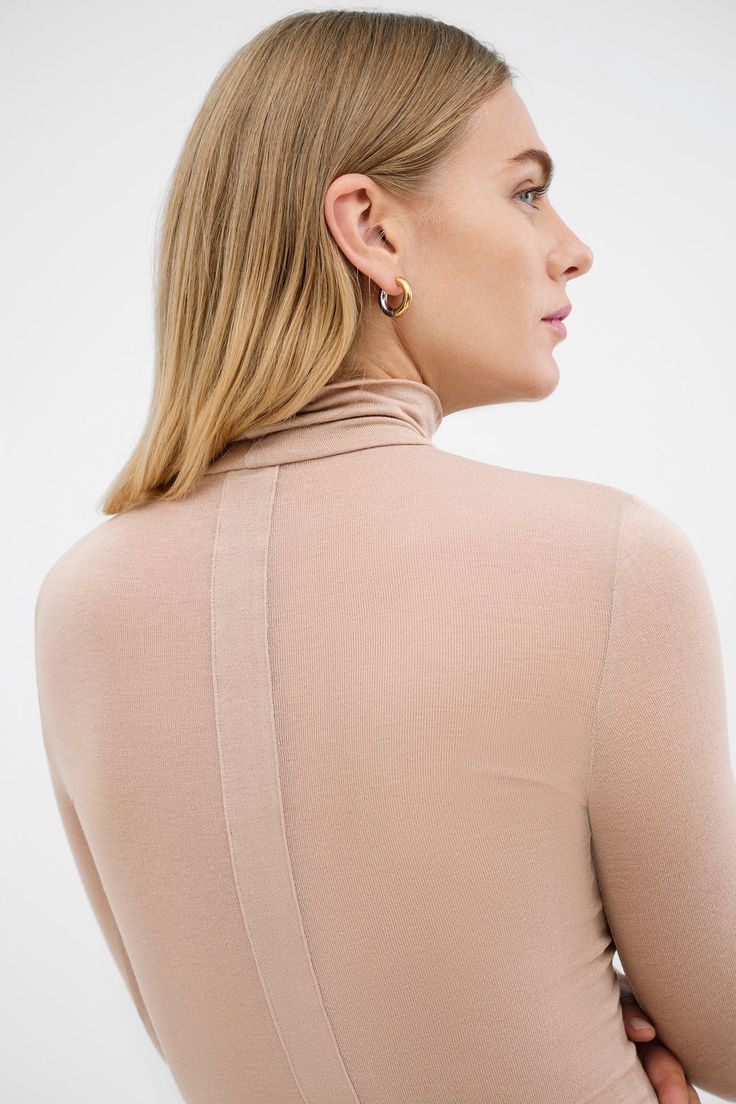 Our Amsterdam Top is a vision of sophistication. Fitting like a second skin in featherlight and high-stretch sheer European jersey, she features a turtleneck, long sleeves and the "pièce de resistance": a geometric vertical panel down the center front and back that provides maximum visual interest. Amsterdam is perfect for dressing up, dressing down, or layering in changeable temps.[SPLIT] Astrid, in pink, is 5'9" (175 cm) tall, wearing size XS. Maritza, in light beige, is 5'9" (177 cm) tall, we Fitted Fine Knit High Neck Turtleneck, Fitted Fine Knit Turtleneck, Chic Fitted Fine Knit Turtleneck, Second-skin Turtleneck For Fall Layering, Modern Turtleneck For Fall, Snug Fit High Neck Turtleneck For Fall, Sleek Long Sleeve Turtleneck For Layering, Winter Second-skin Long Sleeve Turtleneck, Second-skin Long Sleeve Turtleneck For Winter