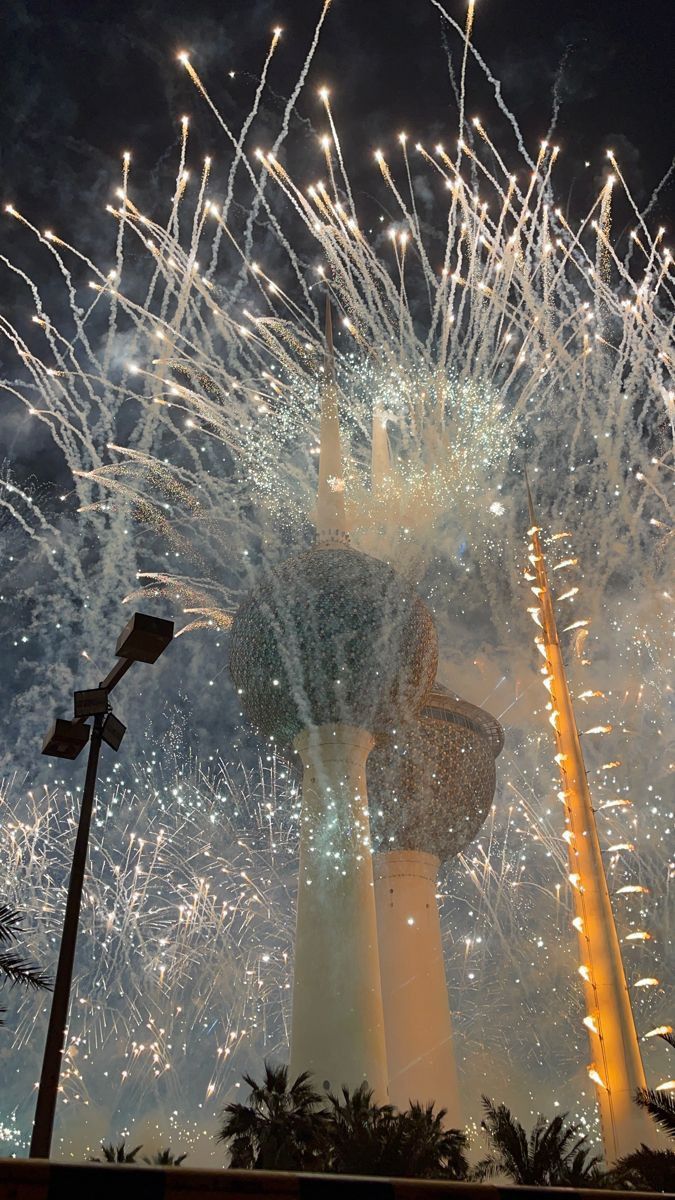 fireworks are lit up in the night sky above a tall tower with a clock on it