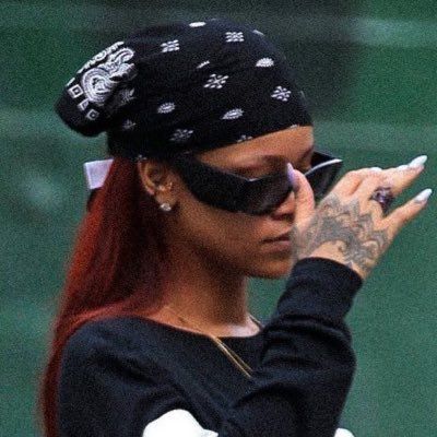 a woman with red hair wearing sunglasses and a bandana talking on her cell phone