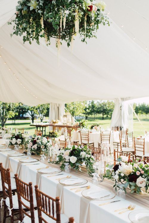 the tables are set up with white linens and floral centerpieces on them