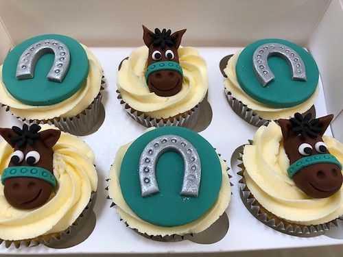 the cupcakes are decorated with frosting and have horse heads on them, as well as numbers