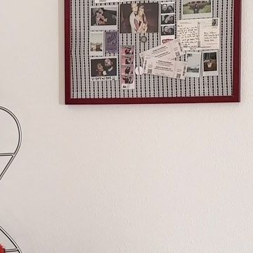 a red chair sitting in front of a white wall with pictures on it and a wire basket underneath