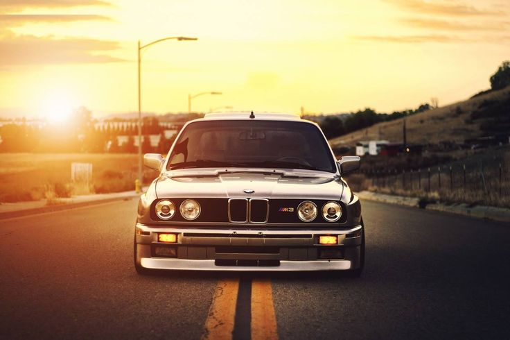 a white car driving down the road at sunset