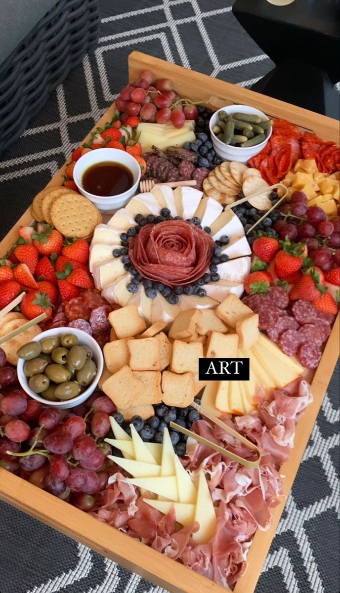 a wooden tray filled with different types of cheeses and fruit on top of a table