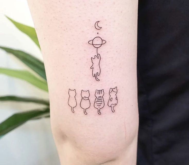 a line drawing tattoo on the arm of a woman's left leg with cats