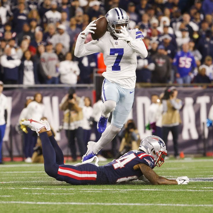 a football player is running with the ball in his hand and another person laying on the ground behind him