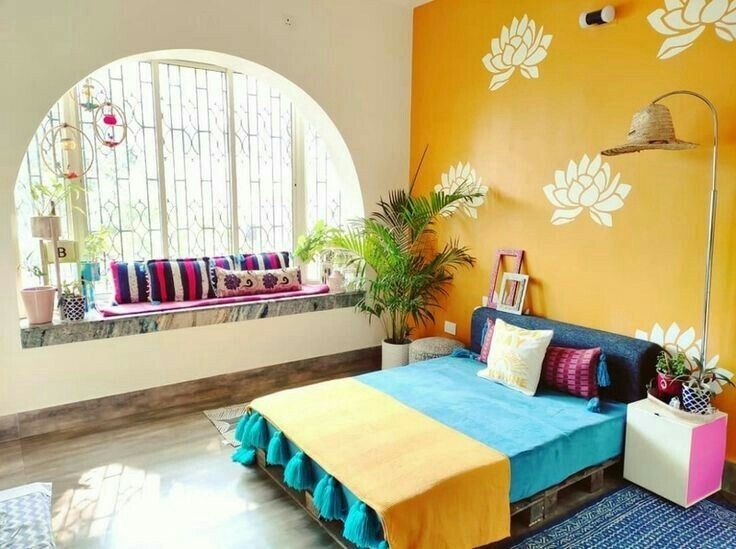 a bed room with a neatly made bed next to a window and potted plants