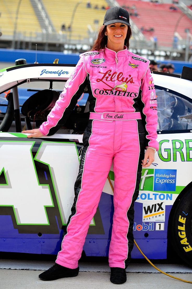 a woman in pink racing suit standing next to a race car