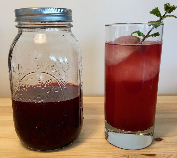 a glass filled with liquid next to a mason jar full of liquid on a wooden table