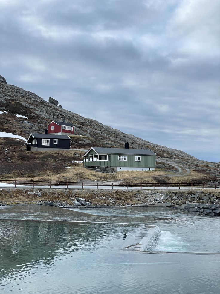 a house on the side of a hill next to a body of water