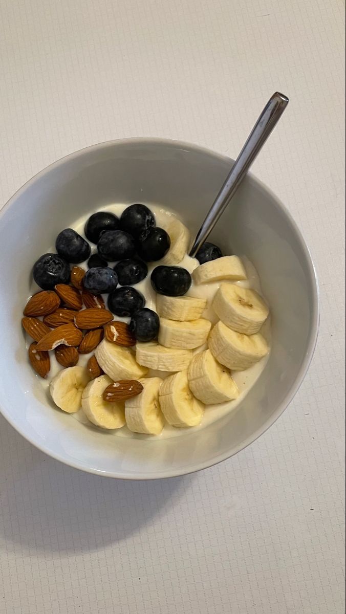 a bowl filled with bananas, blueberries and almonds on top of a table