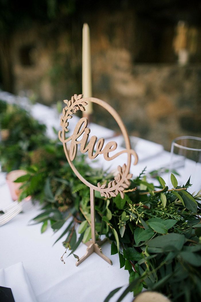 the table is set with greenery, candles and an acrylic sign that says live