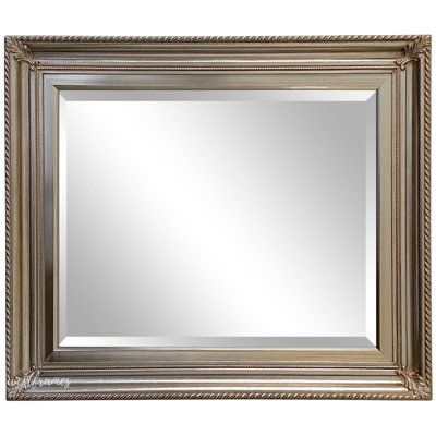 a large silver framed mirror on a white wall with an ornate border around the edges