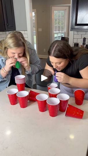 two women sitting at a table with cups and toothbrushes in front of them