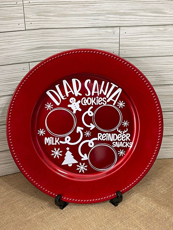 a red plate sitting on top of a wooden table next to a white board with words that read nap santa goes