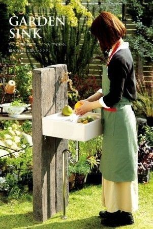 a woman in an apron is washing fruit on a sink outside by the garden sink