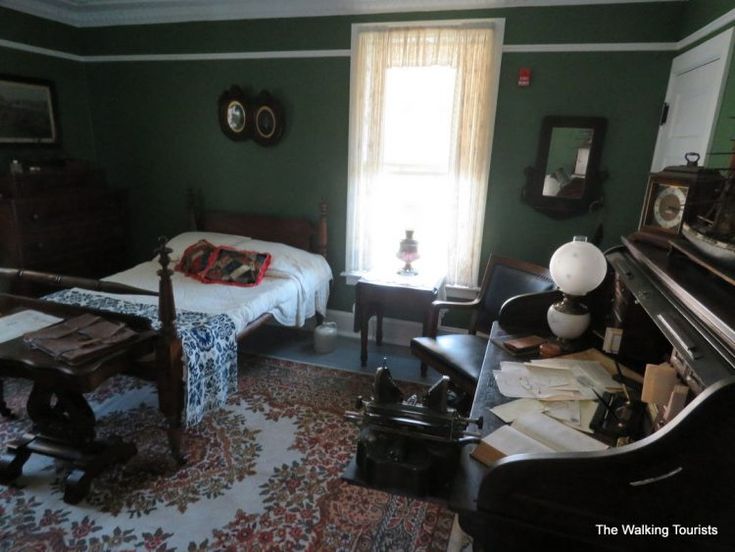 a bedroom with two beds, a piano and other furniture in front of a window