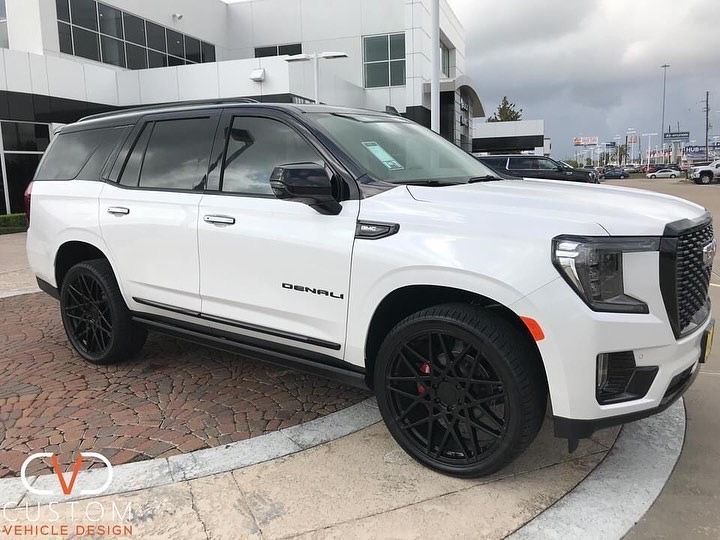 a white suv is parked in front of a building with black rims on it