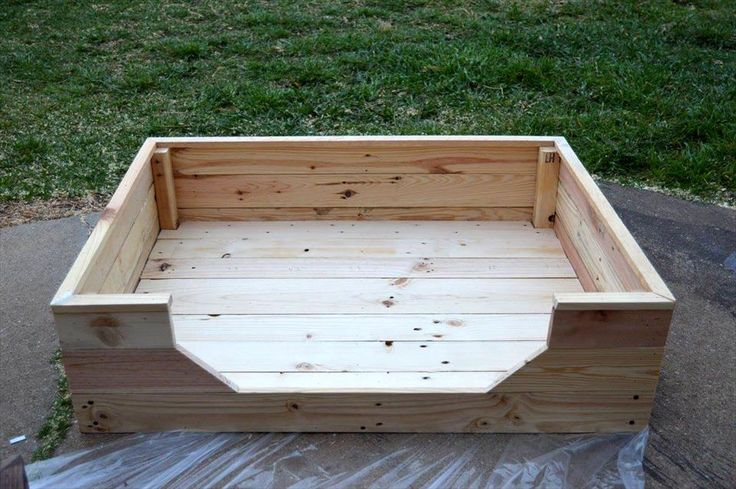 a wooden box sitting on top of a piece of plastic next to some green grass