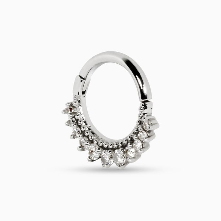 The Melia collection is edge-first with a side of grace. Inspired by the Etruscan art of granulation, this Melia Bead septum ring has small bead details above a row of white diamonds. Larger stones sit at the base of this nose ring, tapering into smaller stones on the ends. A locking hinge clasp secures the ring. Recycled metals White diamonds Approximately .13 total carat weight 8mm diameter Handcrafted and made-to-order Because every piece in our collection is made-to-order, designs can be mod Elegant Hoop Septum Ring With Prong Setting, Elegant White Gold Hoop Septum Ring, Elegant Diamond Septum Ring With Accents, Elegant Cubic Zirconia Septum Ring With Diamond Accents, Elegant Halo Hoop Septum Ring, Diamond Accented Septum Ring, Elegant Diamond Septum Ring, Silver Diamond Ring With Stones, Elegant Round Diamond Septum Ring