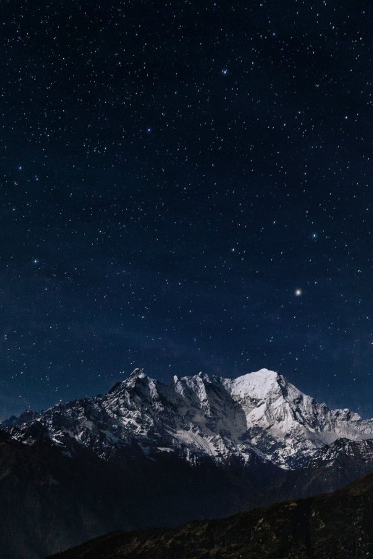 the night sky is filled with stars above mountains