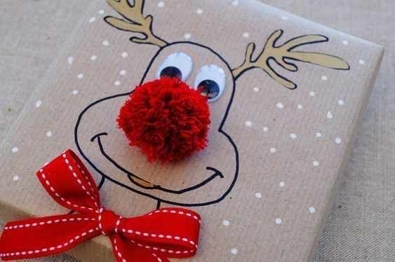 a gift wrapped in brown paper with a red pom - pom attached to it