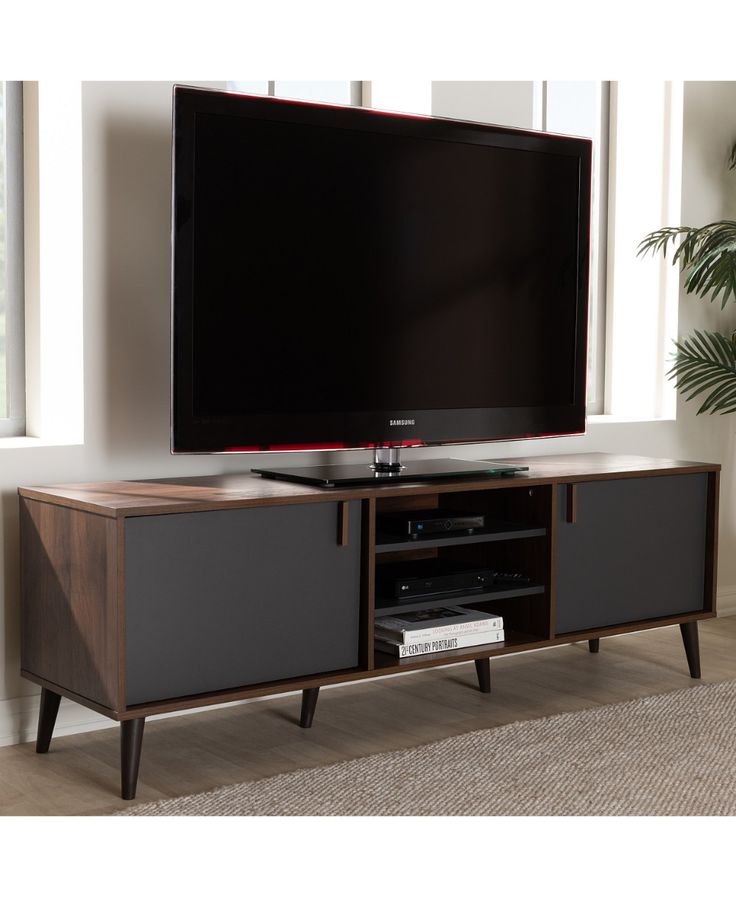 a flat screen tv sitting on top of a wooden entertainment center next to a window