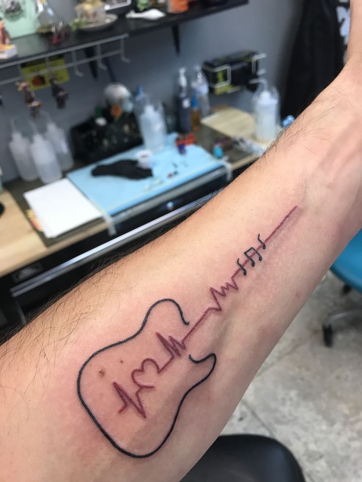 a person with a tattoo on their arm has a guitar and heartbeat written in it