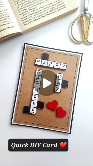 an open book and scissors on a table with a video playing card in the shape of a happy father's day