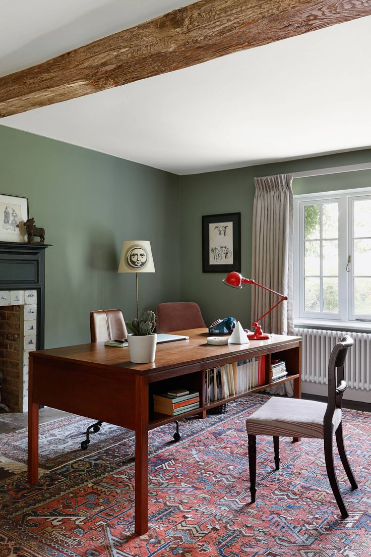 a living room with green walls and an old fashioned desk in the middle of it