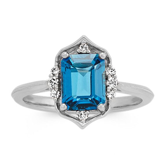 A single emerald cut London blue topaz gemstone (approx. 1.91 carat TW) is beautifully highlighted by eight round diamonds (approx. .10 carat TW) in this vintage style ring. Crafted from quality 14 karat white gold  the 2mm wide rings band features a unique design and has a total gem weight of approximately 2.01 carats. Topaz Diamond Ring, December Birthstone Jewelry, Blue Topaz Gemstone, Vintage Style Rings, White Gold Chains, Platinum Jewelry, Stylish Rings, Wide Rings, Wide Band Rings