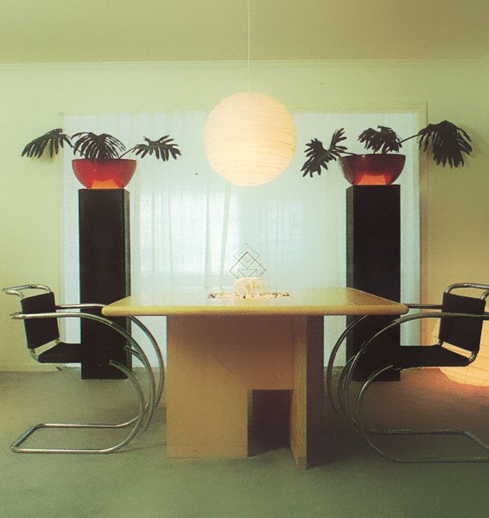 a dining room table with two chairs and a lamp hanging from it's ceiling