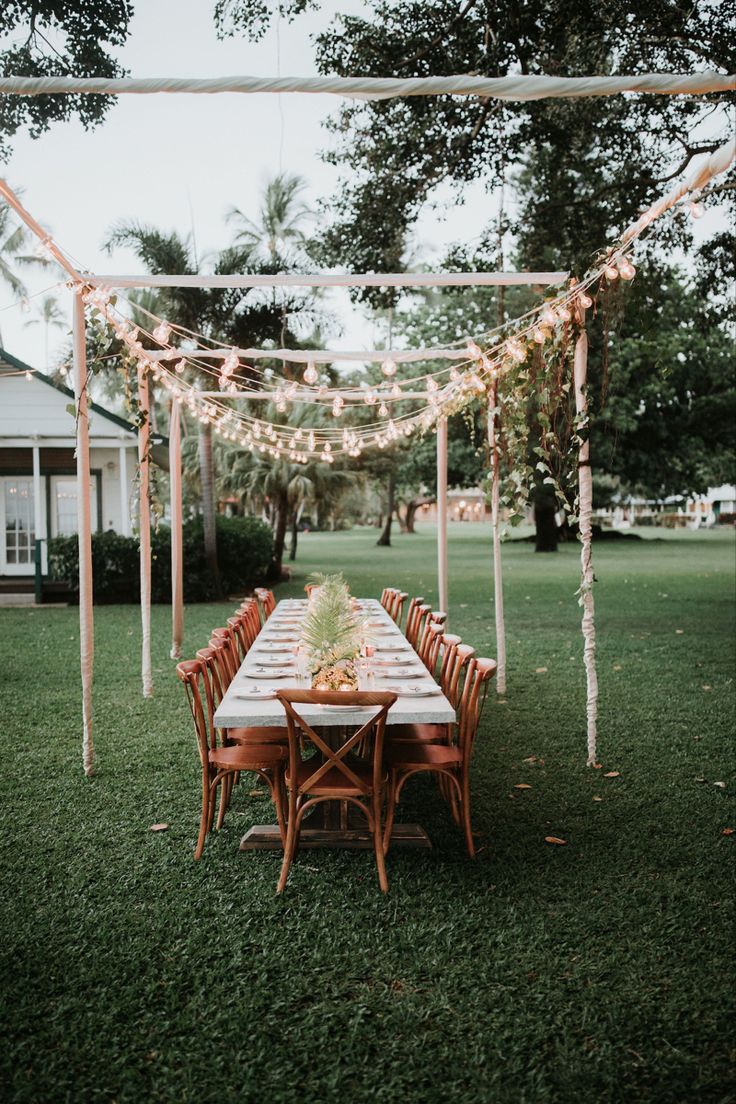 an outdoor dining table set up with string lights