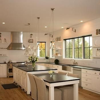 a large kitchen with white cabinets and black counter tops, along with an island in the middle