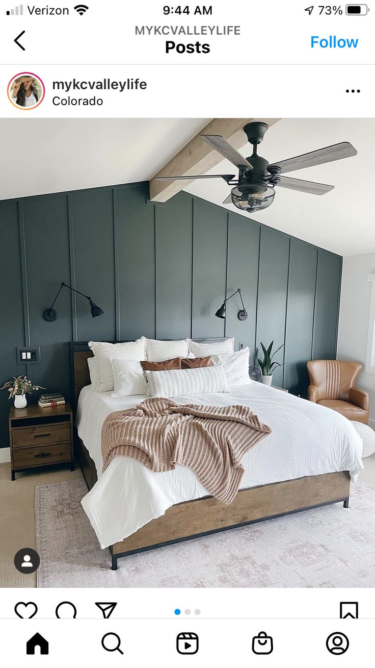 a bedroom with a bed, ceiling fan and two chairs on the other side of the room